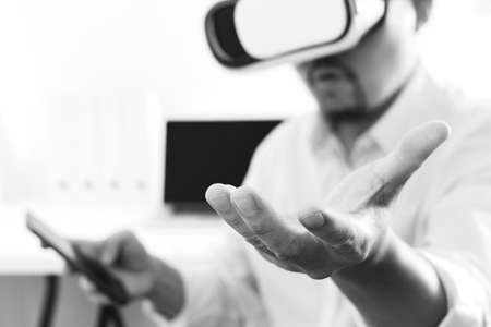 businessman wearing virtual reality goggles in modern office with mobile phone using with VR headset,black and whiteの写真素材