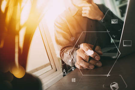 businessman working with mobile phone and digital tablet and laptop computer on wooden desk in modern office with virtual icon diagramの写真素材