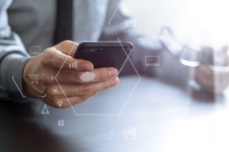 close up of businessman working with mobile phone and eyeglass on wooden desk in modern office with virtual reality icon diagram close up of businessman working with mobile phone and eyeglass on wooden desk in modern office with virtual reality icon diagram