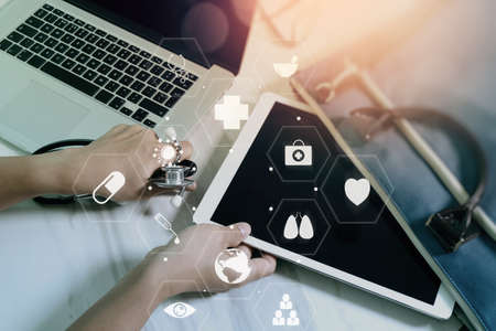 Medical co working concept,Doctor working with smart phone and digital tablet and laptop computer to meeting his team in modern office at hospital with virtual diagramの写真素材