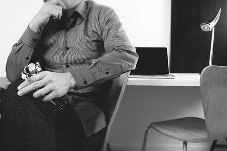 smart medical doctor holding stethoscope and thinking with laptop computer on dark wooden desk in modern office ,black and whiteの写真素材