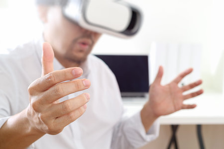 businessman wearing virtual reality goggles in modern office with mobile phone using with VR headset