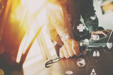 mart medical doctor working with laptop computer and stethoscope on dark wooden desk with virtual reality icon diagramの写真素材