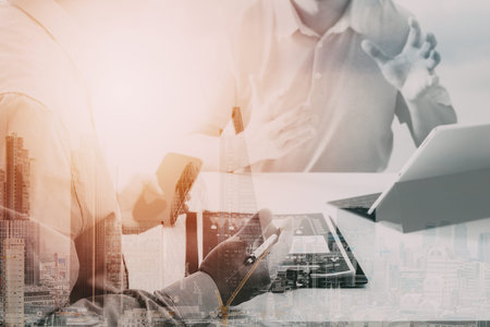 Businessmen working together on a document and using smart phone and digital tablet and laptop...