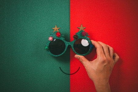 Christmas glasses that decoration with Christmas tree and red ball on hand on green and red ...