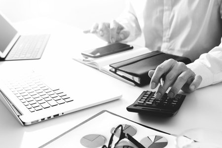 businessman hand working with finances about cost and calculator and latop with mobile phone on...