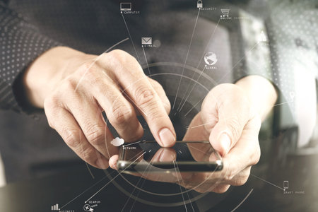 close up of businessman hand working with mobile phone in modern office with VR icon diagram