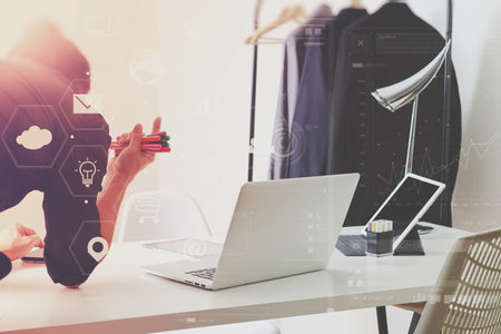 Fashion designer working with mobile phone and using laptop with digital tablet computer in modern...
