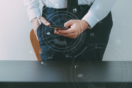 close up of businessman working with smart phone on wooden desk in modern office with virtual icon...