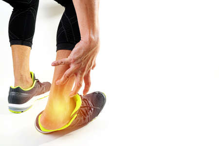 Runner sportsman holding ankle in pain with Broken twisted joint running sport injury and Athletic man touching foot due to sprain on white backgroundの写真素材