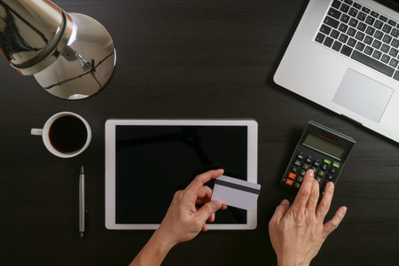 Internet shopping concept.Top view of hands working with laptop and credit card and tablet computer...