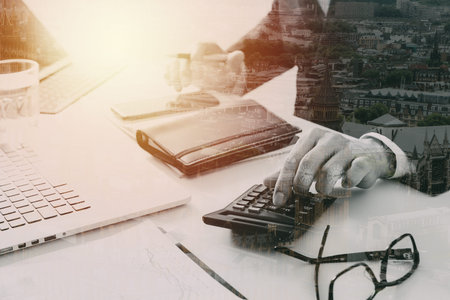 Businessman hand working with finances about cost and calculator and laptop with mobile phone on...