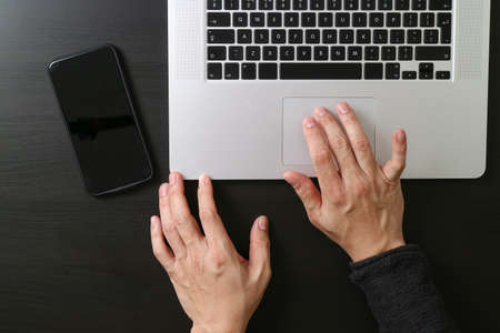 cyber security internet and networking concept.Businessman hand working mobile phone on laptop computer backgroundの写真素材