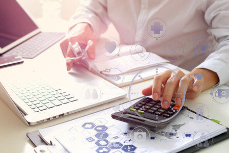 Healthcare costs and fees concept.Hand of smart doctor used a calculator for medical costs in modern hospital with VR icon diagramの写真素材