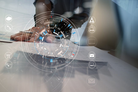 Hands of businessman using mobile phone in modern office with laptop and digital tablet computer in finance team meeting with VR icon diagramの写真素材