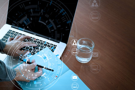 Hands of businessman using mobile phone in modern office with laptop and digital tablet computer in...