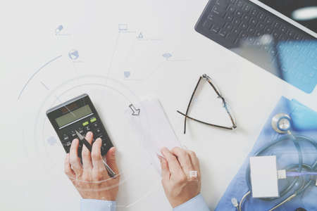 top view of Healthcare costs and fees concept.Hand of smart doctor used a calculator for medical costs in modern hospital with VR icon diagramの写真素材