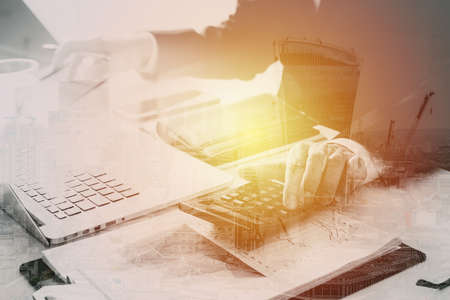 businessman hand working with finances about cost and calculator and latop with mobile phone on withe desk in modern office with buildings exposureの写真素材