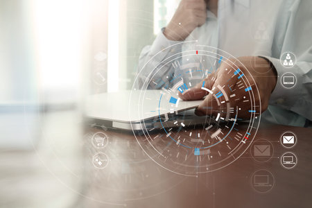 businessman hand working with modern laptop computer in modern office with virtual icon diagramの写真素材