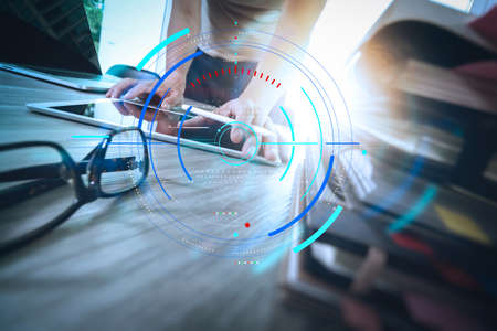 Data statistics charts and key performance indicators diagram.designer hand working with digital tablet and laptop computer and book stack and eye glass on wooden desk as conceptの写真素材