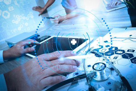 Health care and medical services with circular AR diagram.Medicine doctor hand working with modern computer and digital pro tablet with blank screen with his team on wooden desk as medical conceptの写真素材