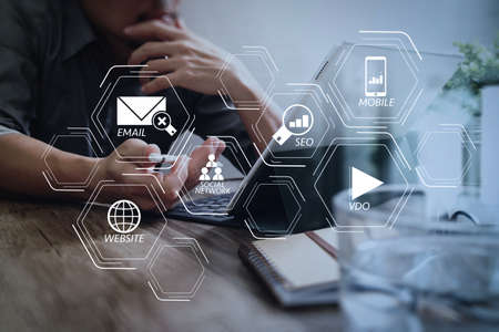 Digital marketing media (website ad, email, social network, SEO, video, mobile app) in virtual screen.success businessman hand using stylus pen,digital tablet docking smart keyboard on wooden desk. Digital marketing media (website ad, email, social network, SEO, video, mobile app) in virtual screen.success businessman hand using stylus pen,digital tablet docking smart keyboard on wooden desk.