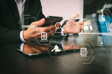 Compliance Virtual Diagram for regulations, law, standards, requirements and audit.businessman working with smart phone and digital tablet and laptop computer in modern office with glass reflected view  の写真素材