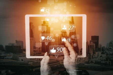 Social media and Marketing virtual icons screen concept.cyber security internet and networking concept.Businessman hand working on mobile phone and digital tablet computer with building exposureの写真素材