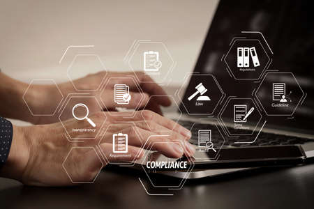 Compliance Virtual Diagram for regulations, law, standards, requirements and audit. businessman hand working with smart phone and laptop and digital tablet computer in modern officeの写真素材