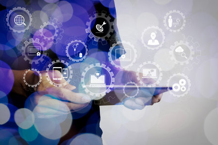 E-learning with connected gear cogs connected diagram virtual dashboard.Double exposure of businessman hand using Tablet computer with colour cloud concept.の写真素材