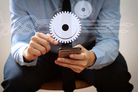 Thinking about structuring virtual diagram of business process with solutions. businessman working with mobile phone and sitting on the chair in modern officeの写真素材