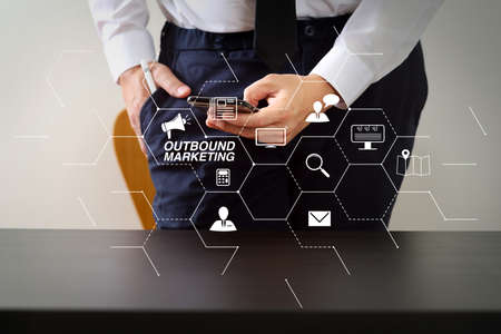 Outbound marketing business virtual dashboard with Offline or interruption marketing.close up of businessman working with smart phone on wooden desk in modern officeの写真素材