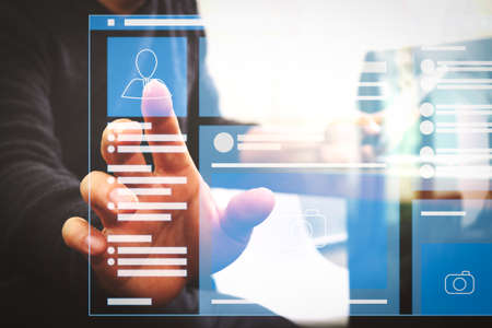 Web page browser of Social media Page VR Interface on the laptop computer.Businessman hand using mobile payments online shopping,pencil,omni channel,laptop computer on wooden desk in modern office.の写真素材