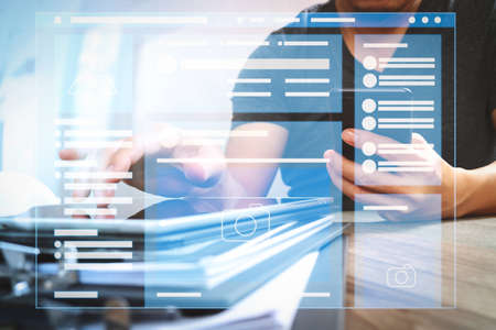 Web page browser of Social media Page VR Interface on the laptop computer.Designer hand using mobile payments online shopping,omni channel,in modern office wooden desk,icons graphic interface.の写真素材