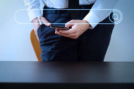 Searching Browsing Internet Data Information Networking Concept with blank search bar.close up of businessman working with smart phone on wooden desk in modern officeの写真素材