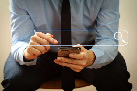 Searching Browsing Internet Data Information Networking Concept with blank search bar.close up of businessman working with mobile phone and sitting on the chair in modern officeの写真素材