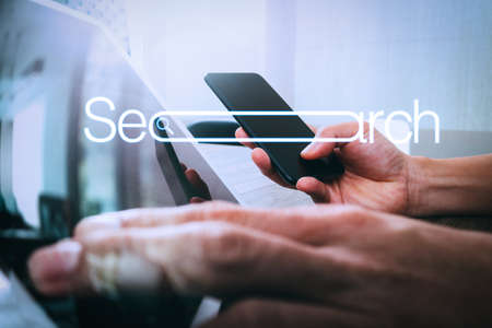 Searching Browsing Internet Data Information Networking Concept with blank search bar.hand using smart phone,mobile payments online shopping with digital tablet docking keyboard computer.の写真素材