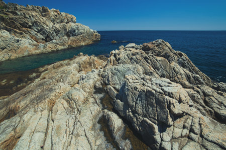 Summer sea landscape, large rocks on the shore close-up, background of the Peninsula with cblue sky.の写真素材