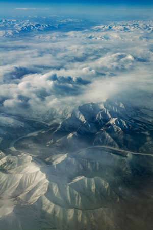 Flight over mountains covered with snow and clouds, Russia, Ural mountains.の写真素材