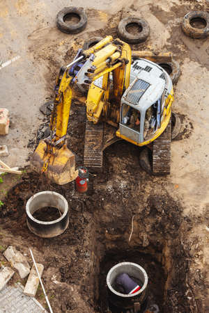 An excavator digs trenches on a construction site. The trench for laying of external sewer pipes.の写真素材