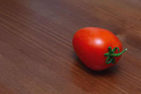 Red tomato on the background of a wooden table.の写真素材