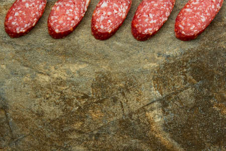Slices of sliced sausage on a background of granite stone, close-up, copy space.の写真素材