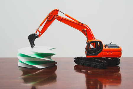 Toy orange excavator in the office on the table with white and green stickers.の写真素材