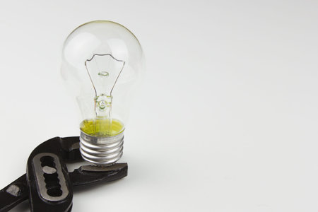 Black pliers and a light bulb on a white background.の写真素材