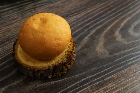 Two hamburger buns lie on a slice of a tree trunk with brown eggs and a glass of milk on a background of textured wood next to oak leaves.の写真素材