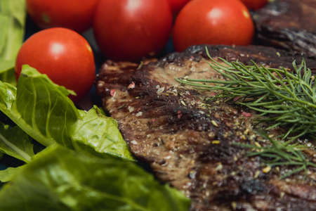 Beef steaks on a plate with cucumber, tomato and herbs.の写真素材