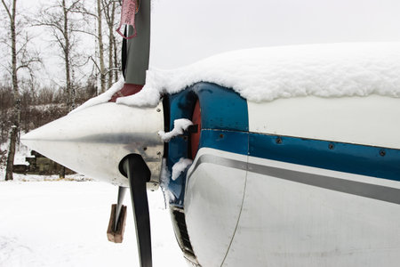 Gray blade, the hood of a small private plane covered with snow, winter in bad weather at the...