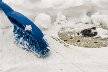 Blue removal brush removes snow from the airplane wing near the gas station neck on a winter day, snowfall, non-flying weather, close-up.の写真素材