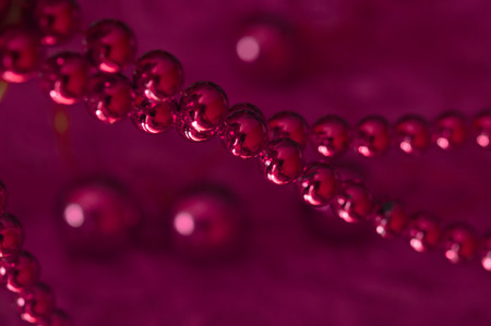 Christmas pink garland made from small red beads.On A pink Background. New year toy. Toned photoの写真素材