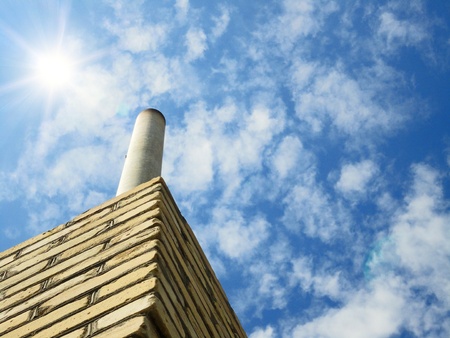                      Chimney against a blue sky with clouds and sun          の写真素材